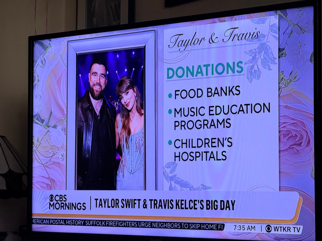 A television screen displaying a segment about Taylor Swift and Travis Kelce, featuring a photo of them together and text highlighting their donations to food banks, music education programs, and children's hospitals.